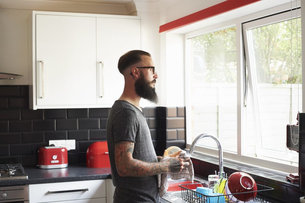 Hombre en cocina lavando platos